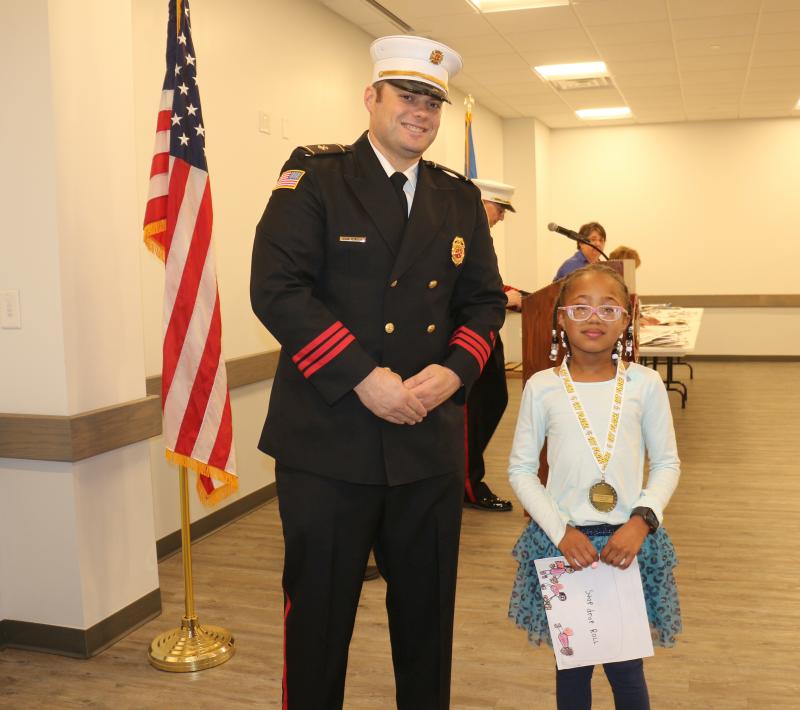 H.O. Brittingham Elementary first-grader Savannah Lee is congratulated by MFD President Brian Reynolds Jr. for winning first place.